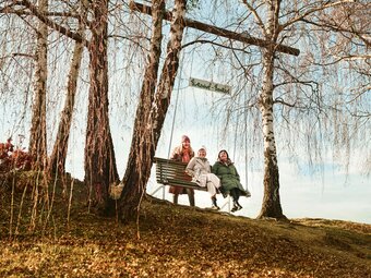 3 ladies sit on a large swing along the wine adventure trail in Bad Loipersdorf in the Thermen- & Vulkanland region of Styria