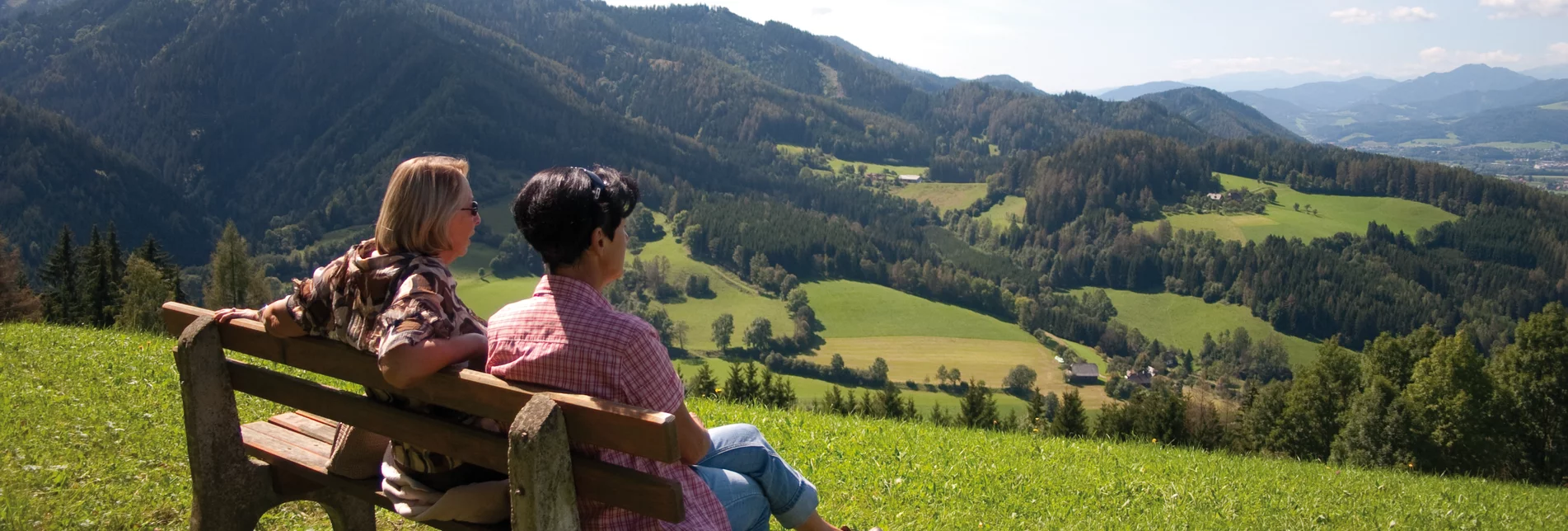 Ein Mann und eine Frau sitzen auf einer Bank und schauen in die Ferne