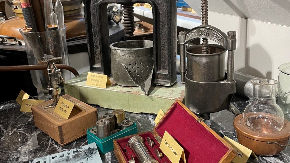 Verschiedene historische Geräte in der Adler Apotheke, inklusive Pressen und diverse Behälter. | © Adler Apotheken Museum