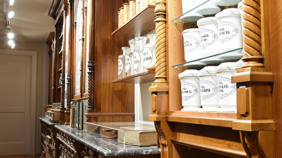 Einblick in die Adler Apotheke mit antiken Behältern und Regalen. | © Adler Apotheken Museum