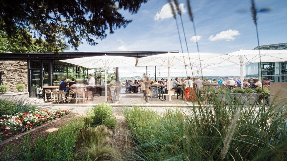 Gemütliche Terrasse mit Gästen, Sonnenschirmen und schöner Pflanzenlandschaft. | © aiola