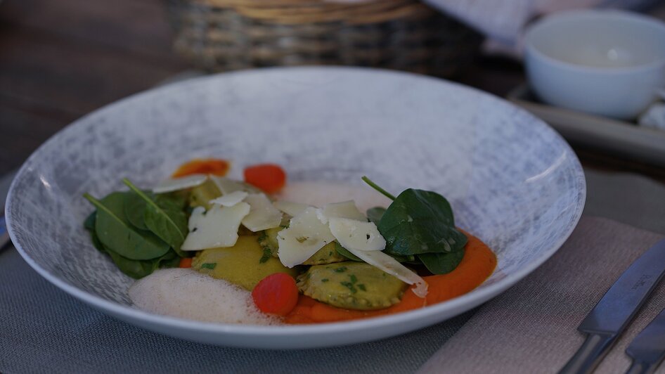 Ein raffinierter Teller mit Ravioli, Spinat, Tomaten und Parmesan. | © aiola