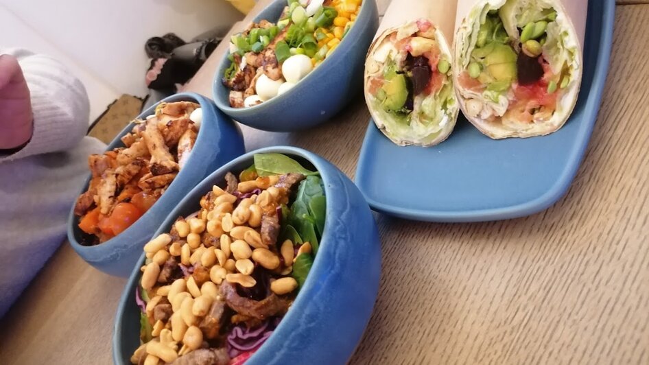 Bunte Salate und Wraps auf einem Tisch, ideal für eine gesunde Mahlzeit. | © Alpoke - K. van Kerken