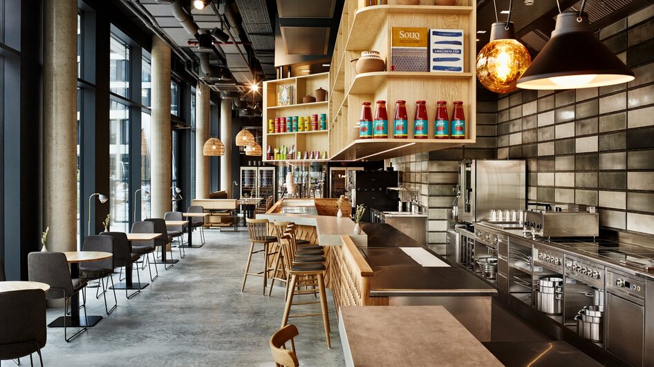 Modernes Restaurant mit Barbereich und offener Küche.