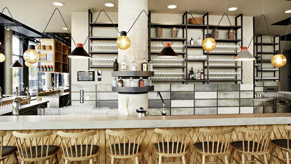 Moderne Bar mit Holzstühlen, eleganter Einrichtung und Regalen.
