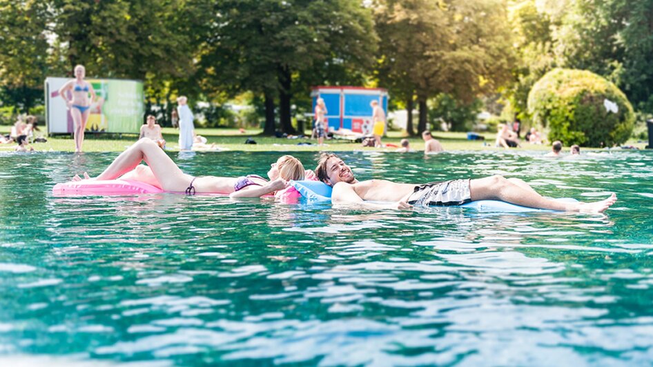 Paar schwimmt auf Luftmatratzen im Bad Straßgang, Graz, bei Sonnenschein. | © Holding Graz - Joel Kernasenko