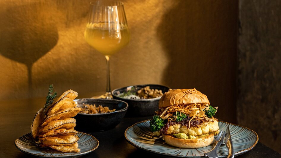 Ein leckerer Burger mit Beilagen und Wein in einem Restaurant.