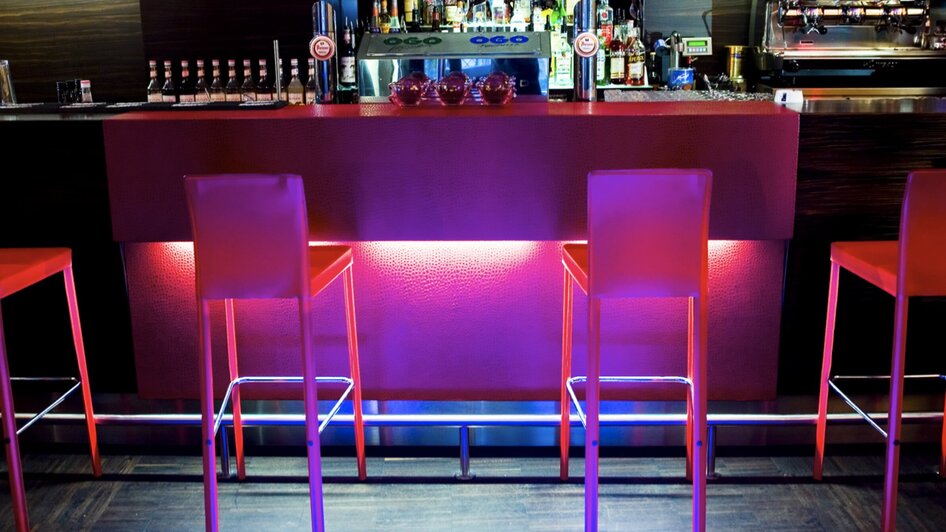 Stylische Bar mit beleuchtenden Stehtischen und Getränkeregalen. | © Cafe Glockenspiel