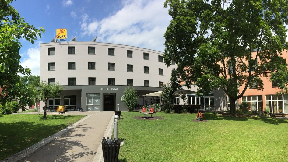 JUFA Hotel Graz City mit Grünflächen und Spielplatz. | © JUFA Hotel Graz City