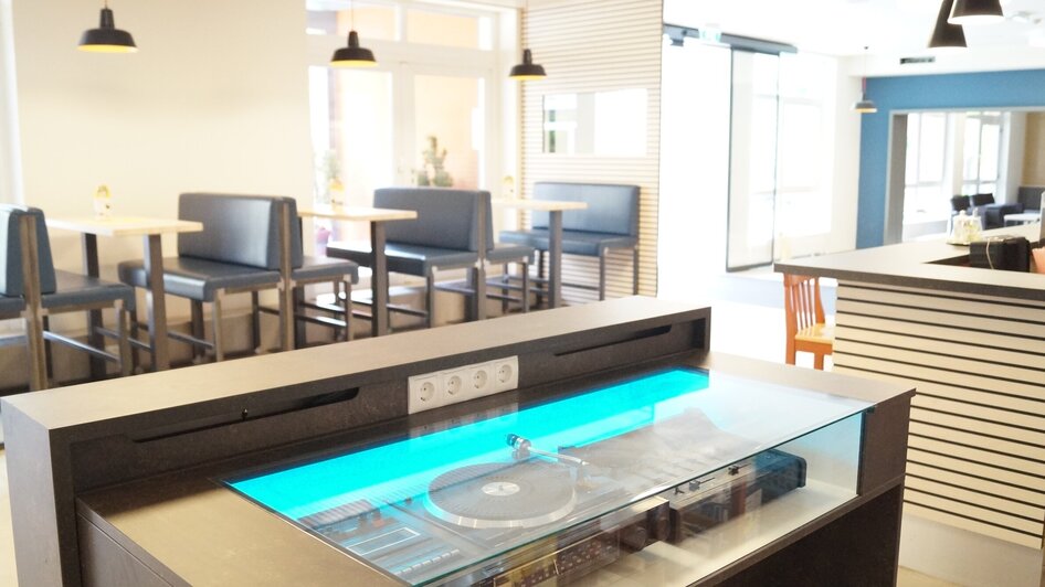 Ein innovativer Raum mit einem Plattenspieler und stilvollen Möbeln. | © JUFA Hotel Graz City