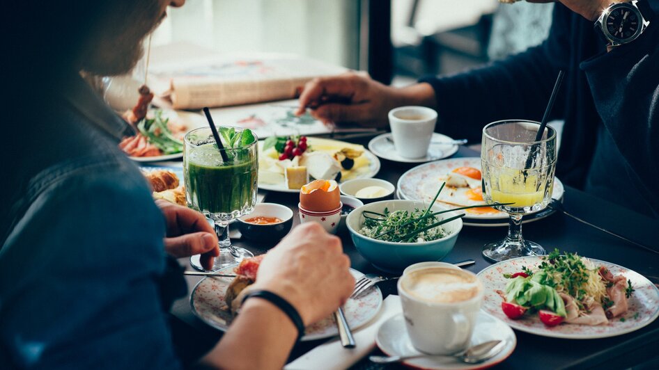 Zwei Personen genießen ein Frühstück mit Getränken und frischen Speisen.