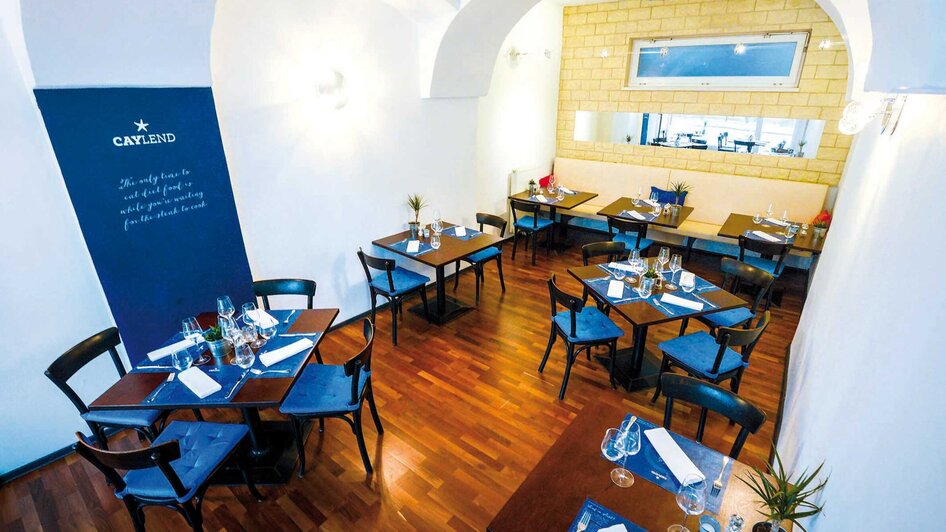 Elegantes Restaurant Caylend mit Tischen und modernen Stühlen.