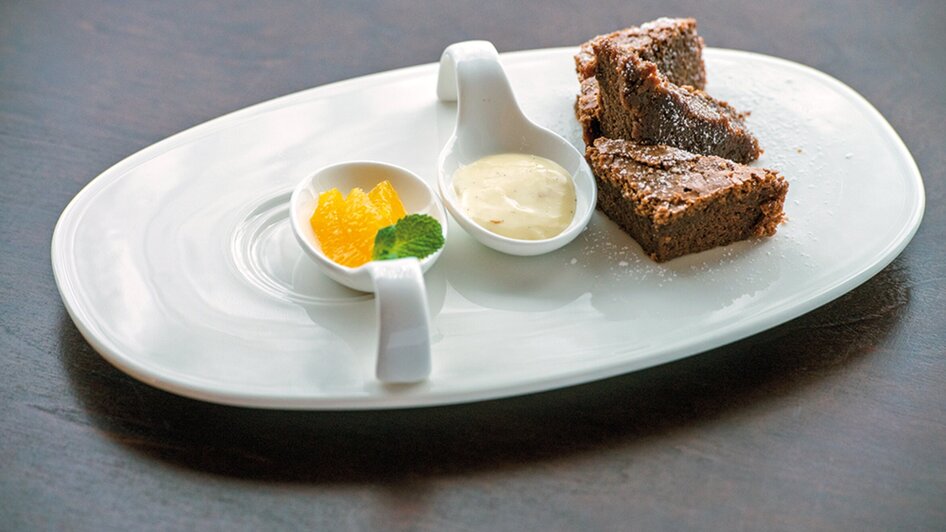 Dreieckiger Schokoladenkuchen mit Vanilleeis und Orangenstücken.
