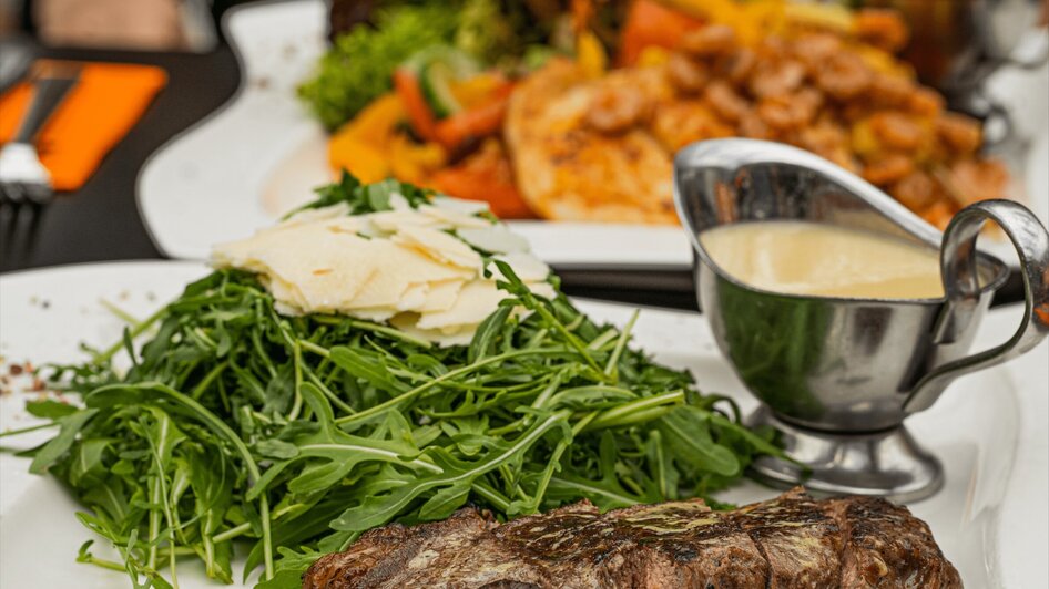 Ein saftiges Steak mit frischem Rucola und Käse, serviert mit einer Sauce.