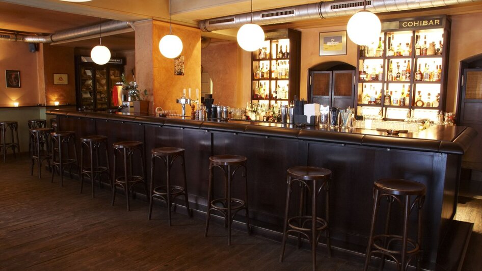 Gemütliche Bar mit Holztheke und großen Leuchten. | © cohibar