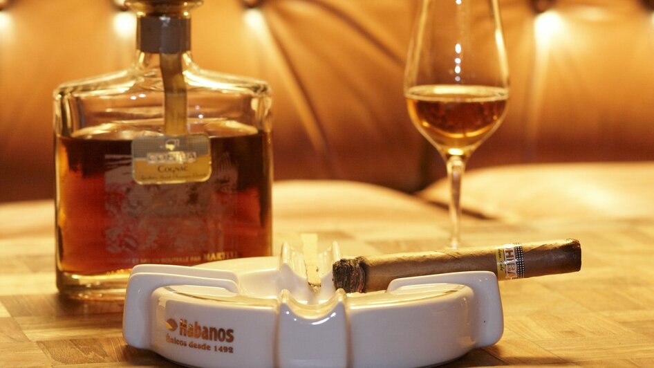 Whisky, Zigarre und Glas auf einem Tisch in gemütlicher Atmosphäre. | © cohibar