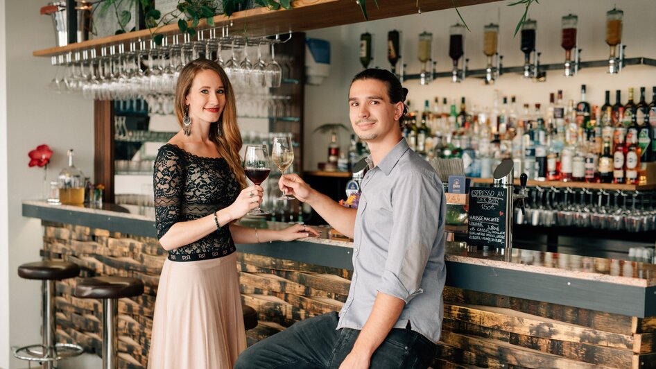 Zwei Personen stoßen an der Bar mit Getränken an. | © R&D Gastro OG