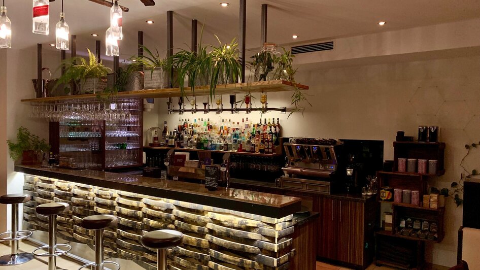 Moderne Bar mit einer Auswahl an Getränken und Pflanzen im Hintergrund. | © R&D Gastro OG