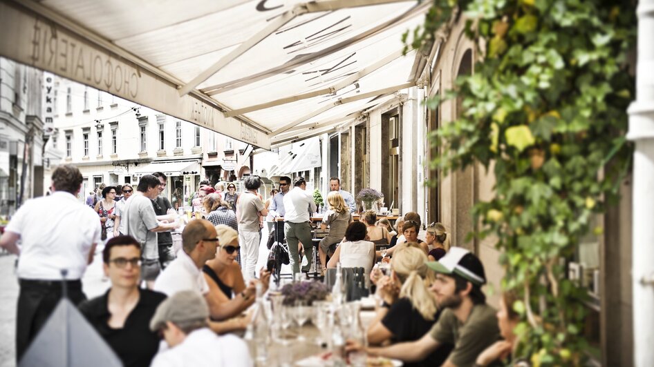 Belebte Straßencafé-Szene in Graz, entspannte Atmosphäre.