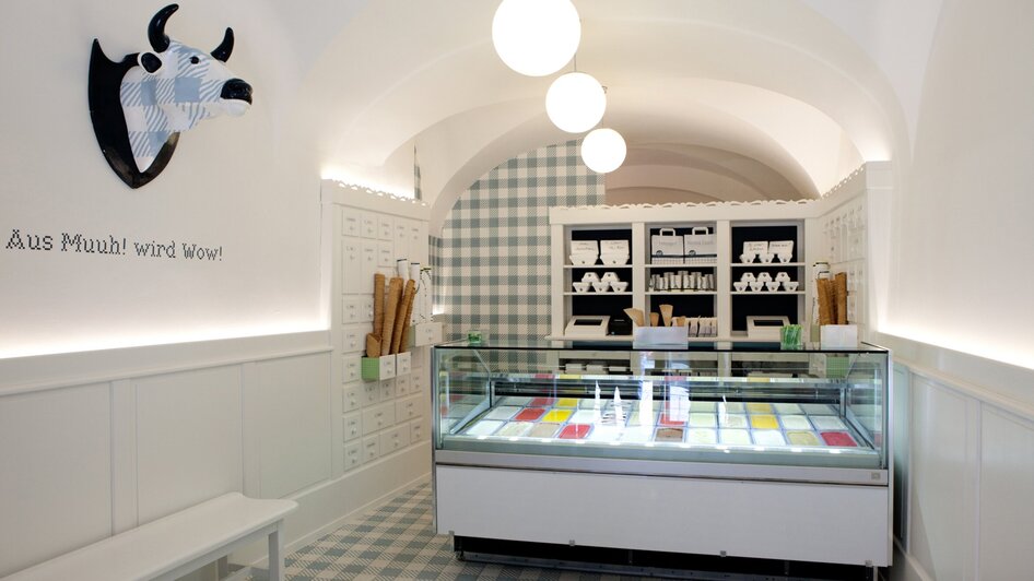 Innenansicht des Eisgeschäfts mit buntem Eis und einem Kuh-Kopf an der Wand.