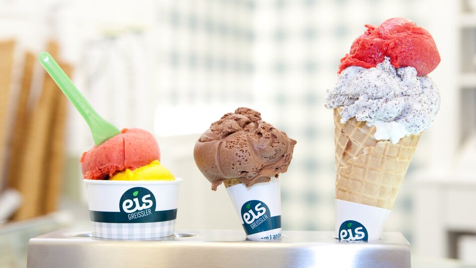 Ein Becher mit Himbeereis, eine Tüte mit Schokoladeeis und eine Tüte mit Himbeer- und Mohneis in der Eis-Greisslerei in Graz.