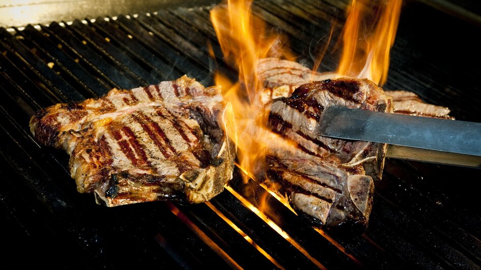 Gegrillte Steaks auf dem Grill mit Flammen.
