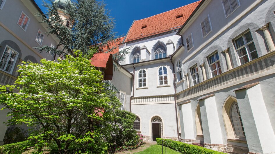 Ansicht des Franziskanerklosters in Graz mit Garten und Gebäuden. | © Graz Tourismus - Harry Schiffer