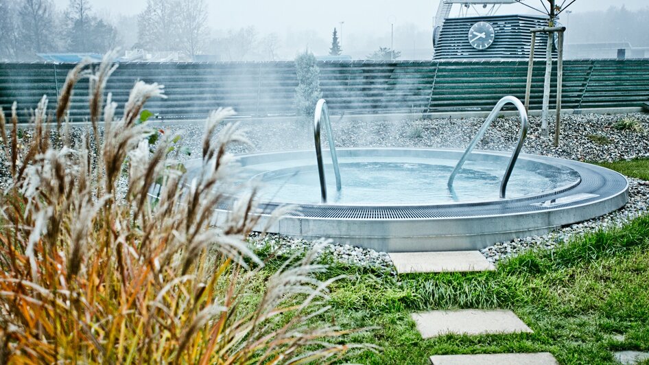 Whirlpool im Freien mit Dampf, umgeben von Pflanzen in Graz.