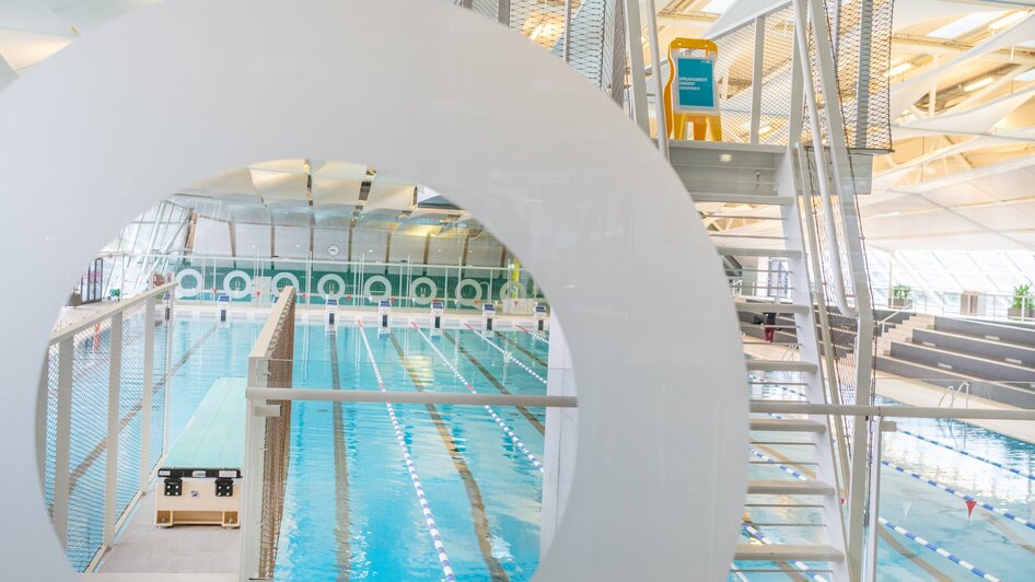 Innenansicht des Schwimmbads Auster in Graz, mit Schwimmbecken und Sprungturm.
