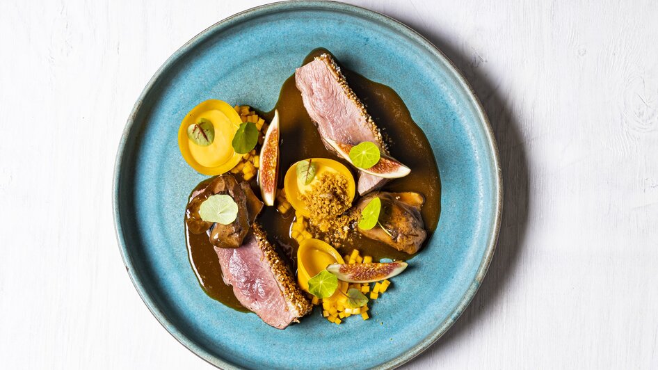 Ein kunstvoll angerichteter Teller mit Fleisch, Früchten und Sauce. | © Genießerei am Markt
