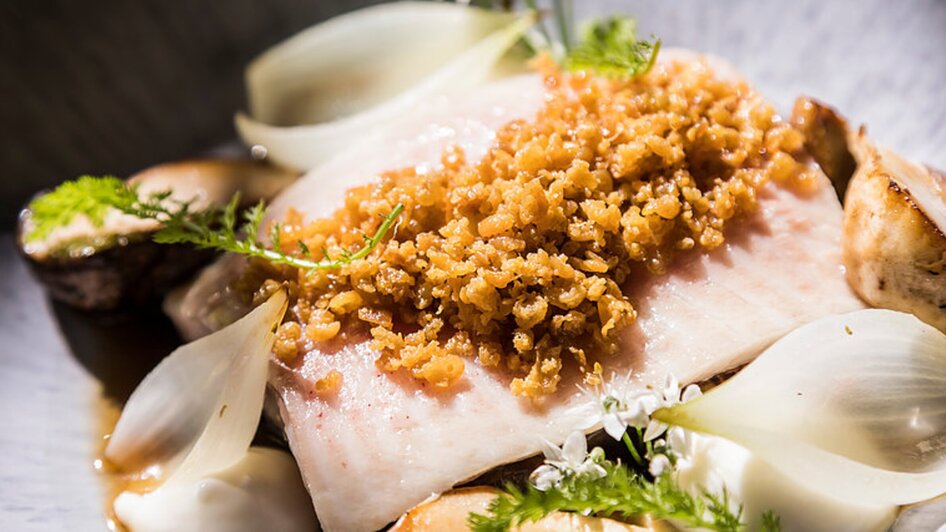 Ein gegrillter Fisch mit knuspriger Kruste, serviert mit Zwiebeln und Kräutern. | © Genießerei am Markt