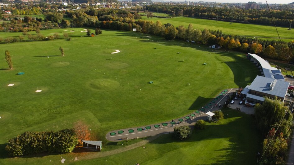 Luftaufnahme des Golfzentrums Andritz in Graz mit Grünflächen und Golfabschlagplätzen.