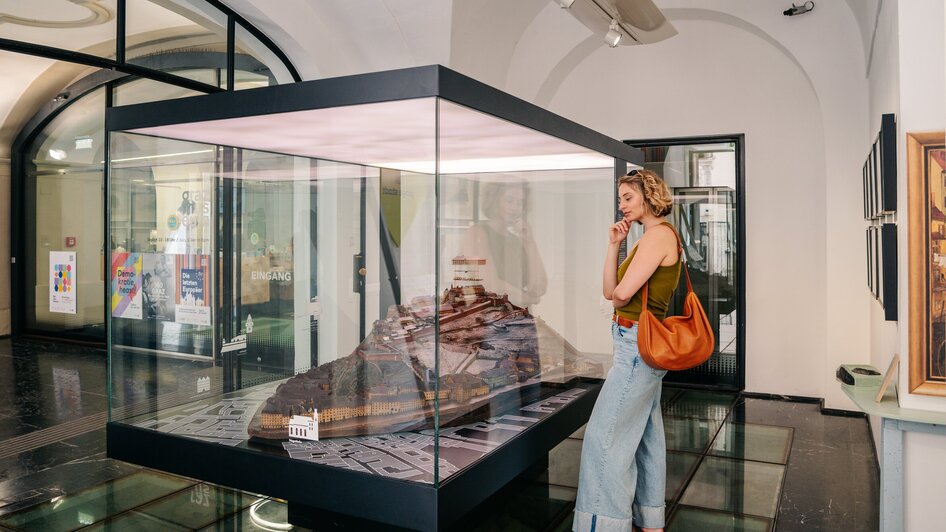 Frau betrachtet ein Modell im Graz Museum. | © Graz Tourismus - Mias Photoart