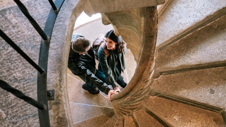 Ein Paar hält sich an der Doppelwendeltreppe in Graz fest.