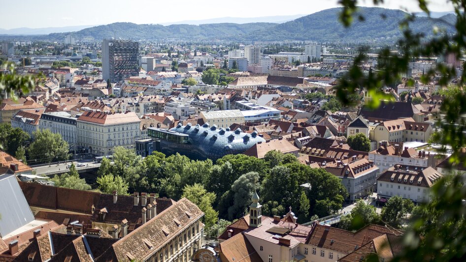 Blick auf Graz mit traditionellen Dächern und dem Kunsthaus Graz.