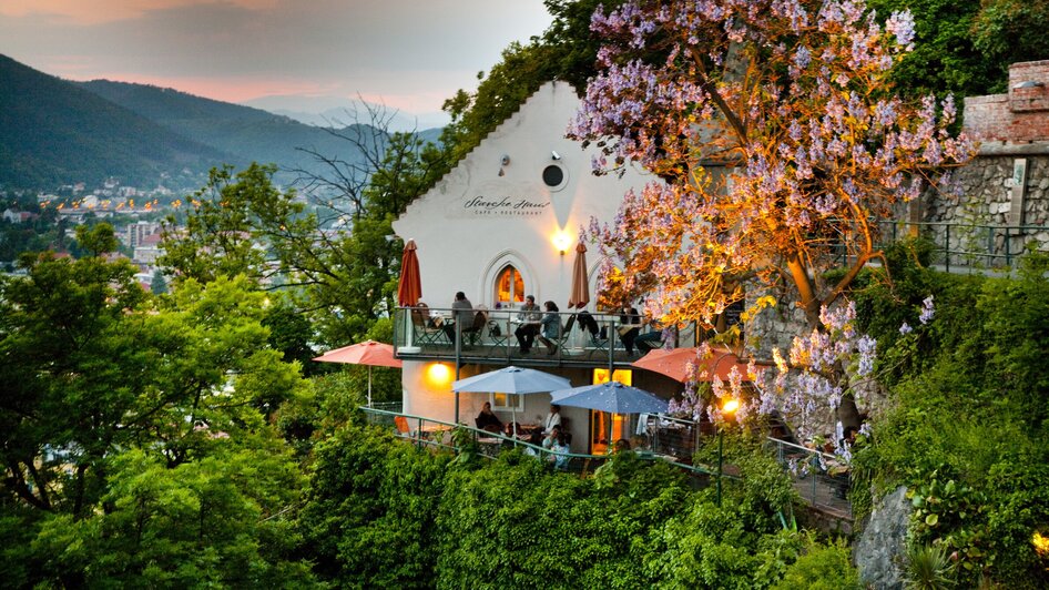 Das Starcke Haus in Graz mit Terrassen und blühendem Baum.