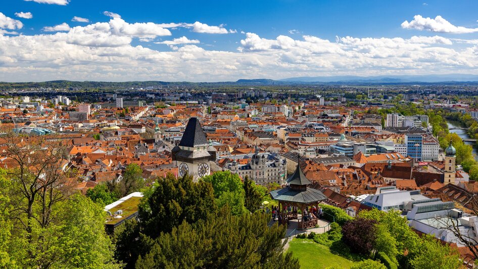 Blick über Graz mit dem Uhrturm am Schlossberg und der Mur.
