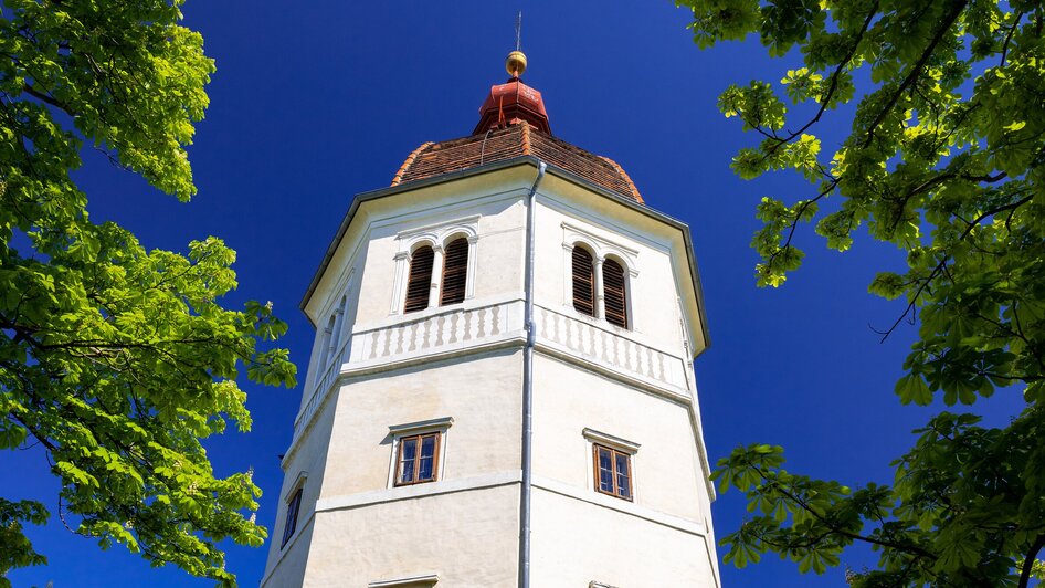 Glockenturm am Grazer Schlossberg, umgeben von Bäumen.