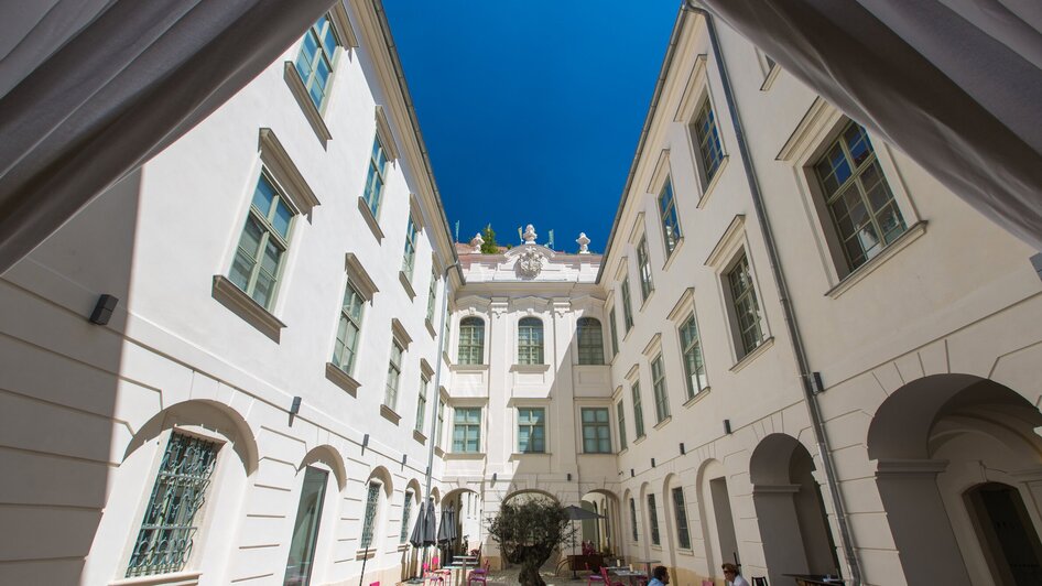 Ein Blick in einen Innenhof mit Cafés, einem Baum und strahlend blauem Himmel in Graz. | © Graz Tourismus - Harry Schiffer