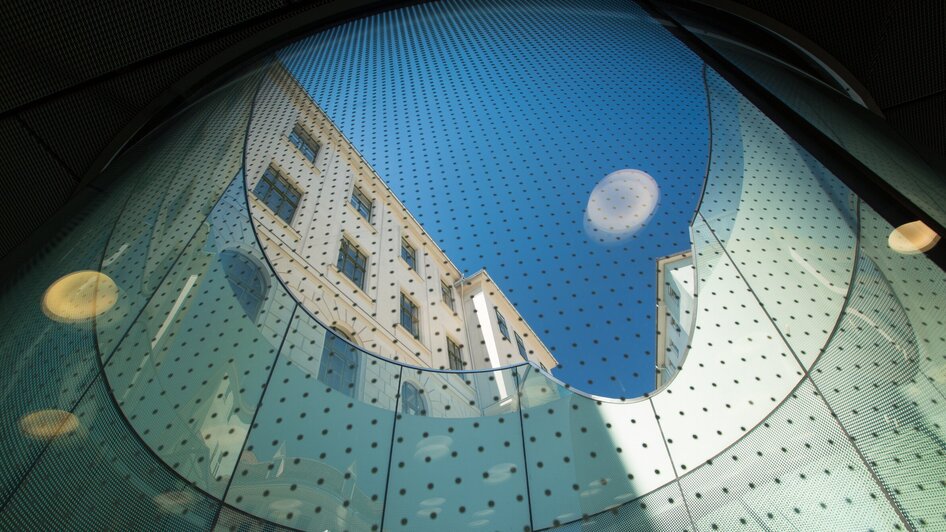Blick durch einen Glasbogen auf das Joanneumsviertel in Graz.