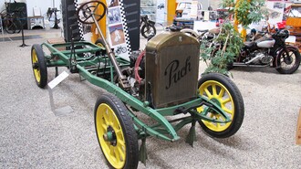 Ein historisches Fahrgestell von Puch mit grünem Rahmen und gelben Rädern in einem Museum. | © Johann Puch Museum