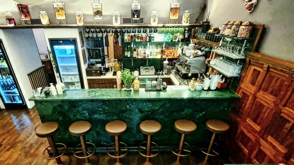 Ein stilvolles Bistro mit einer eleganten Bar, vielen Getränken und gemütlichen Sitzen.
