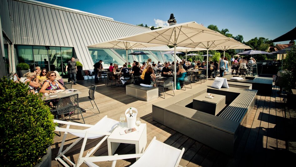 Belebtes Dachterrassen-Café mit Gästen zum Essen und Trinken in Graz.