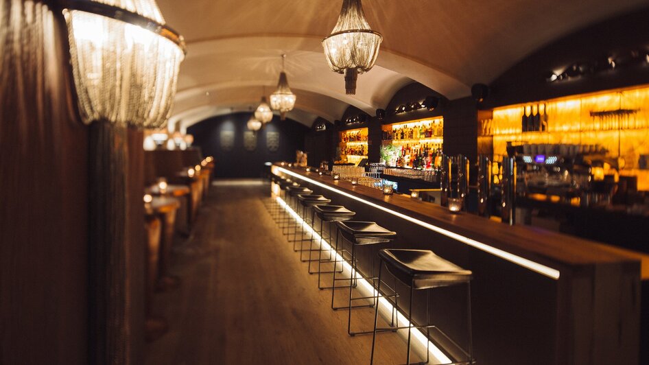 Elegant beleuchtete Bar mit Sitzplätzen und Getränken. | © Katze Katze