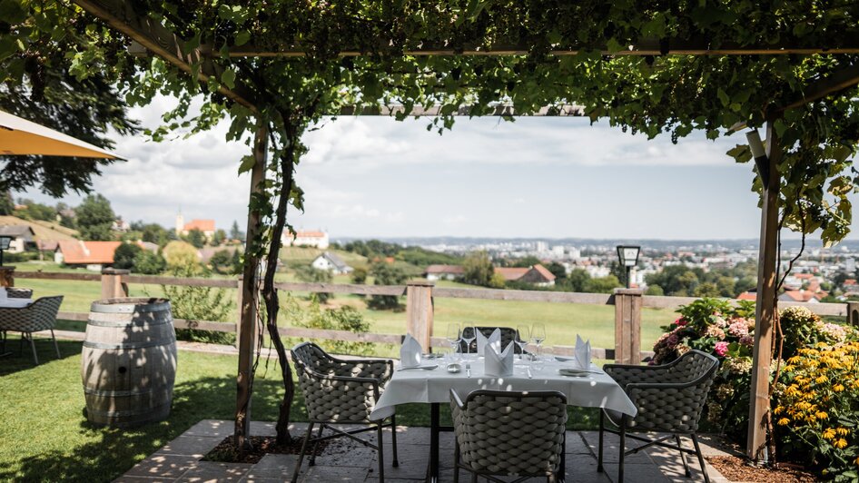 Ein Restaurant unter Weinreben mit Blick auf Graz.