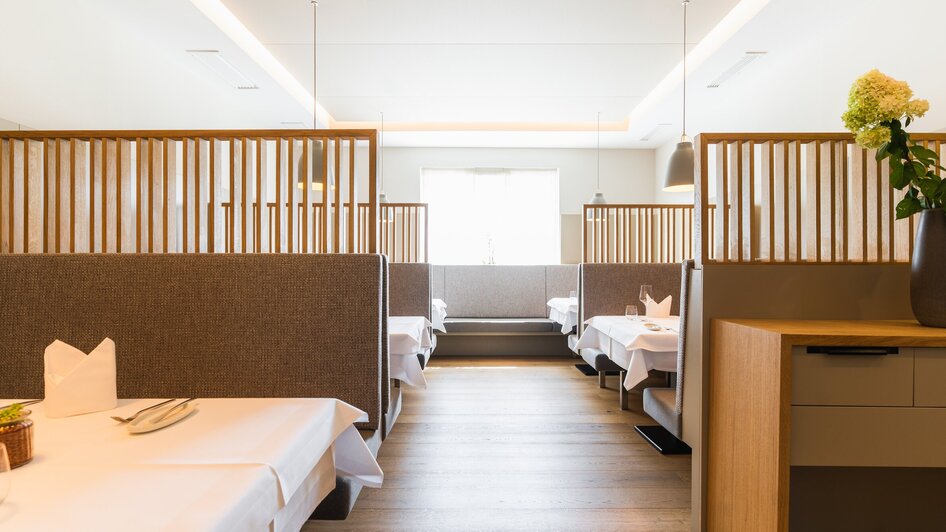Elegantes Restaurantinterieur mit Holzelementen und Tischen.