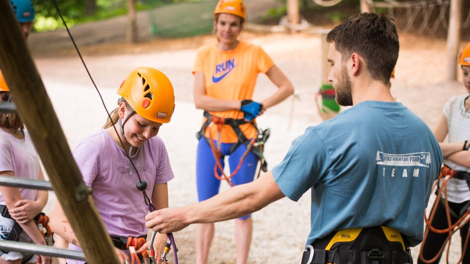Gruppenaktivität im Kletterwald mit Instruktor und Teilnehmern.