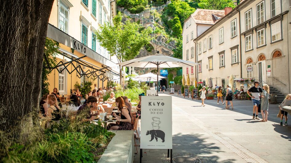 Gemütliches Restaurant am Schlossbergplatz in Graz mit Gästen und grüner Umgebung. | © mpview
