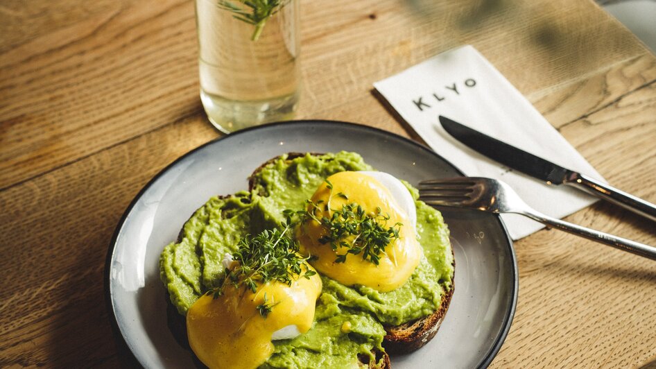 Avocado-Toast mit pochierten Eiern und einem Getränk. | © Aaron Jiang
