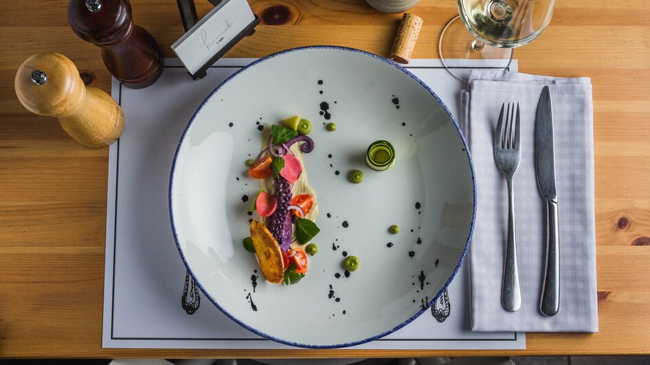 Ein kunstvoll angerichteter Teller mit frischem Fisch und Gemüse.